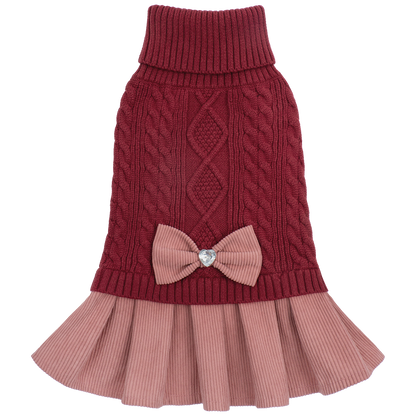 Cutout of burgundy cable knit sweater dress with pink skirt and bow on black background