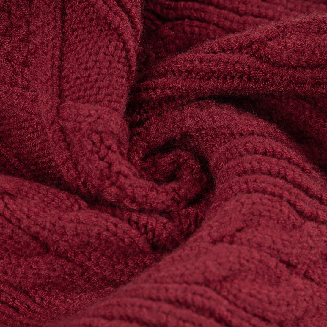 Close-up of burgundy knitted fabric showing raised cable stitch texture