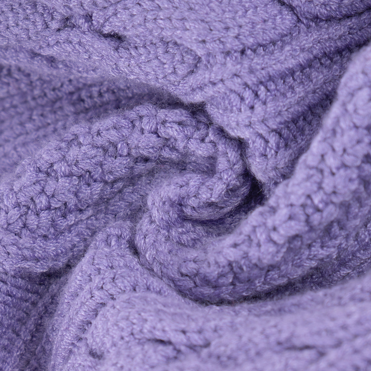 Close-up of raised cable stitches in light purple knit fabric