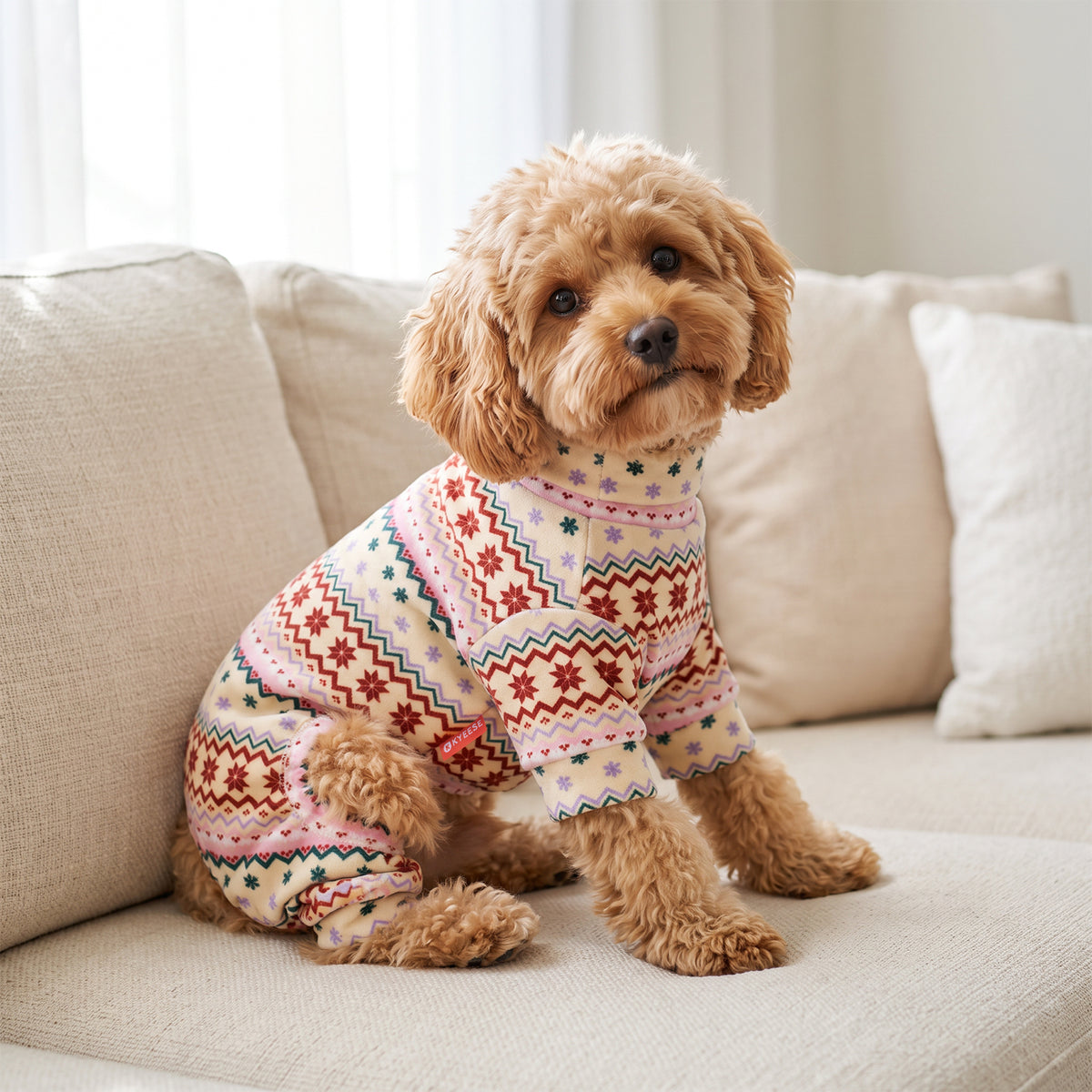 Pink Snowflake Dog Christmas Pajamas, cream and pink Fair Isle snowflake pattern, dog wearing the pajamas in a holiday or home setting
