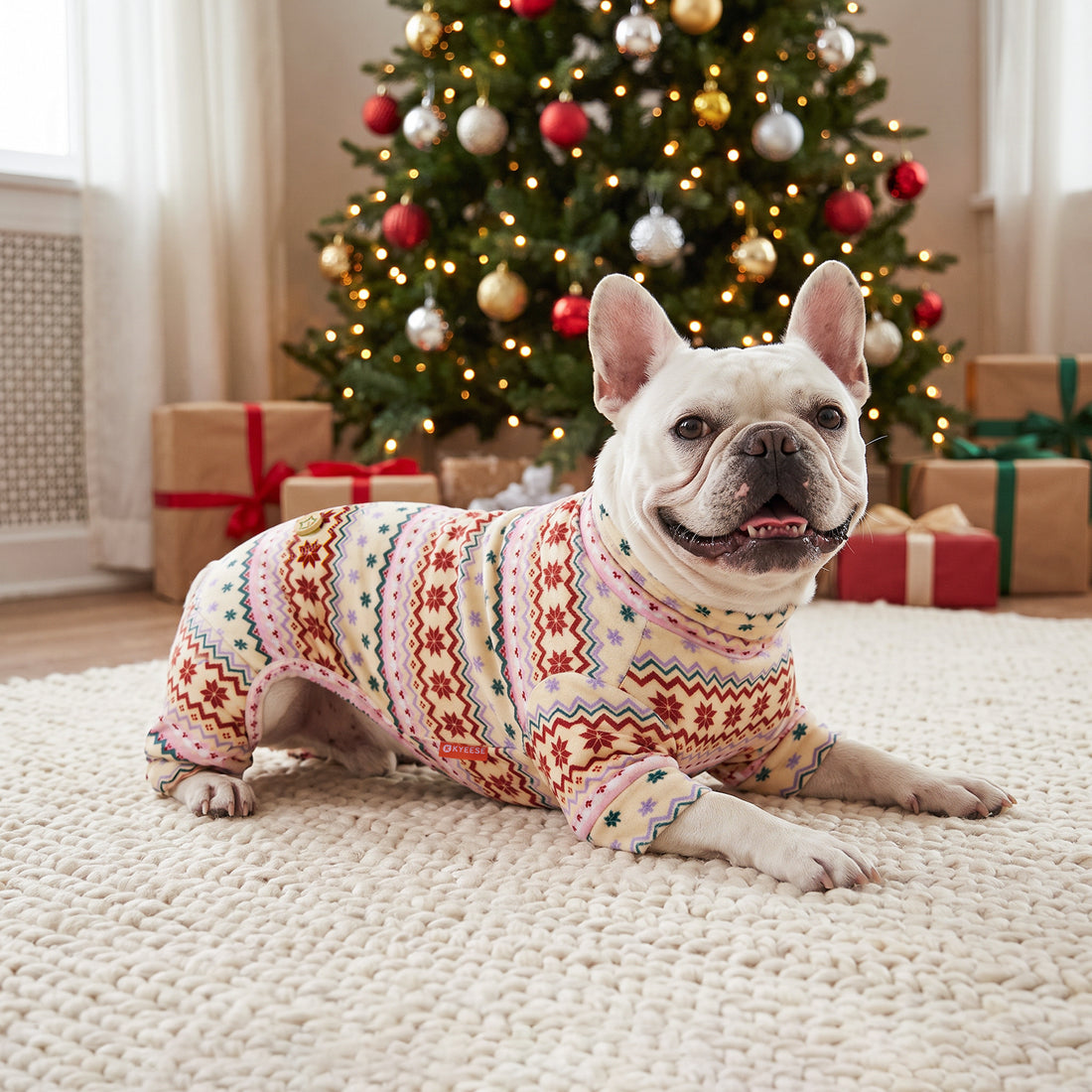 Pink Snowflake Dog Christmas Pajamas, cream and pink Fair Isle snowflake pattern, dog wearing the pajamas in a holiday or home setting