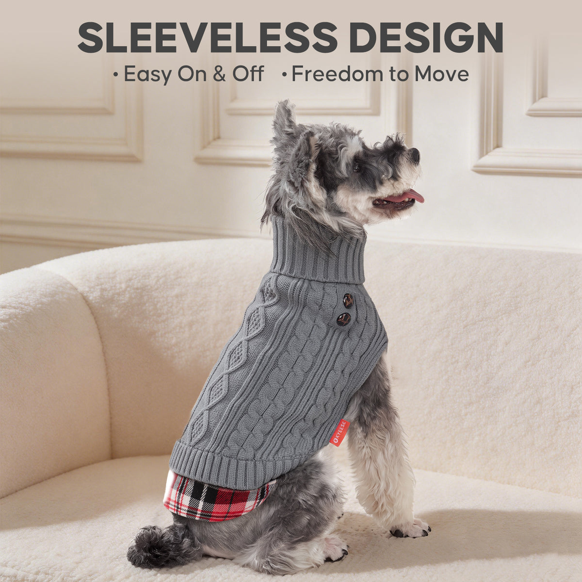 Grey cable knit turtleneck dog sweater with plaid hem worn by a Schnauzer sitting on a sofa