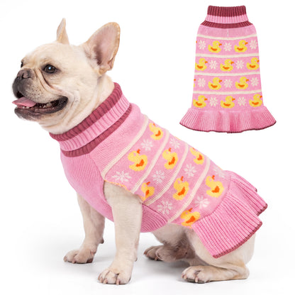 Cream French bulldog wearing pink knit dress with yellow ducks beside a flat lay