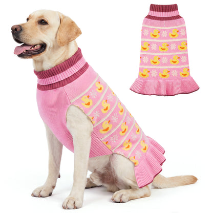 Tan dog seated in a pink duck pattern sweater dress beside a flat lay